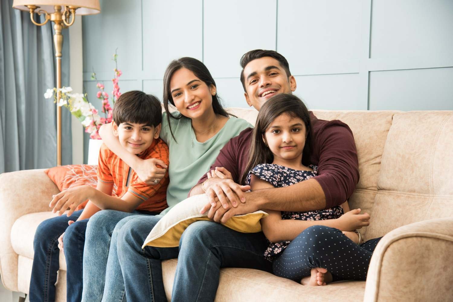 portrait-happy-indian-asian-young-family-while-sitting-sofa-lying-floor-sitting-against-wall-compressed